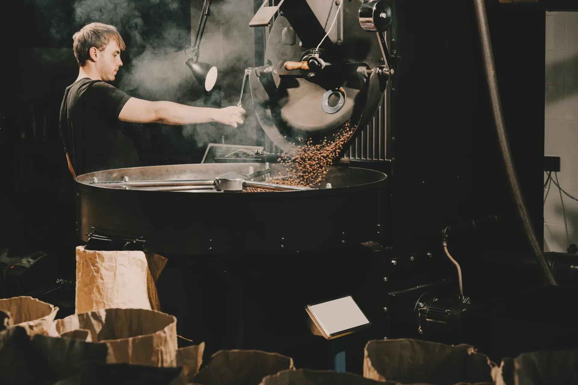 Coffee roaster emptying freshly roasted beans into a cooling tray.