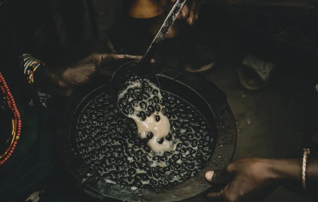 The thick, sacred brew of Buna Kela — coffee berries roasted, pounded, and mixed with butter — shared among family and community as a symbol of unity and gratitude.
